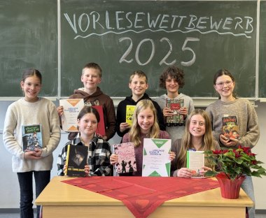 Zu sehen sind Lena, Andreij, Jannis, Franz, Anna K., Ella, Anna H., Luisa. Sie sitzen vor einer Tafel an einem Tisch.