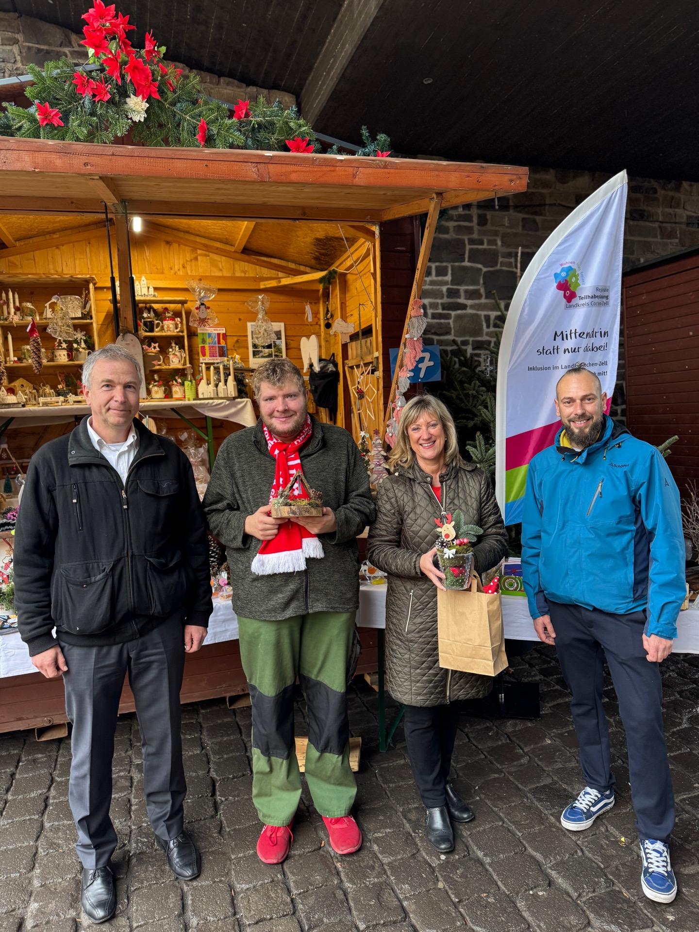 Besuch auf dem Weihnachtsmarktstand des Steuerungskreises zur Teilhabe von Menschen mit Behinderung: v.l.: Achim Wagner (Geschäftsbereichsleiter Kreisverwaltung Cochem-Zell), Sven Temmen, Landrätin Anke Beilstein, Christian Greulich (Werkstattleiter Mosellandwerkstätten Zweigstelle Kloster Eber-nach)