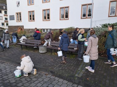 Zu sehen sind mehrere Kinder die mit Eimern vor dem Kreishaus herumlaufen und Müll vom Boden sammeln