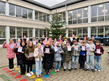 Sportabzeichen 2025 Zu sehen sind die Jahrgangsstufen 5-7. Sie stehen draußen vor einem Weihnachtsbaum. Die Kinder halten ihre Urkunden für das Sportabzeichen in den Händen.