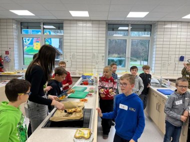 Verpflegung Zu sehen sind Gründschüler in der Schulküche stehen.