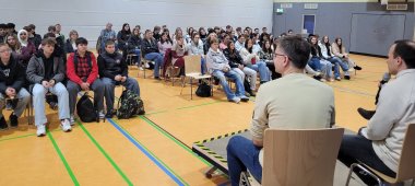 Austausch mit Politikern Zu sehen sind die Klassen 9,10,12 der Realschule plus und Fachoberschule Kaisersesch. Sie sitzen auf Stühl in einer Turnhalle. Im Vordergrund sitzen die Landtagsabgeordneten.
