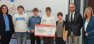 Gewinner Realschule plus Lutzerath Ulmen Zu sehen ist eine Personengruppe. Rechts außen steht Bettina Pellio. Daneben stehen Schüler der Realschule plus Lutzerath Ulmen zusammen mit ihrem Lehrer. Links außen ist Landrätin Frau Beilstein zu sehen.