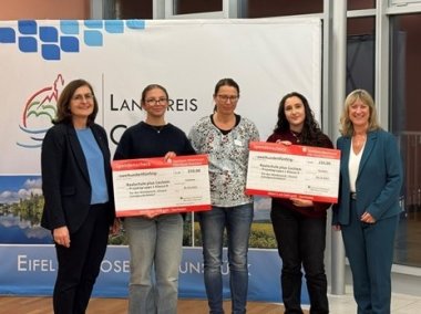 Auf dem Bild sehen Sie Frau Bettina Pellio (Sparkasse), Frau Hoepp-Wiselka (Lehrerin Realschule Plus Cochem), Frau Landrätin Anke Beilstein und zwei Schülerinnen der Realschule Plus Cochem, die jeweils einen Scheck in Höhe von 250 € in der Hand halten.