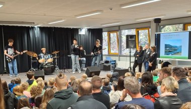 Zu sehen ist eine Personen Gruppe, die der Schülerband zuhört.