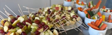 Zu sehen sind Traubenkäsespieße, mini Burger und Karotten, sowie Gurkensticks.