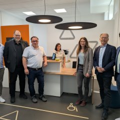 Foto FGZ Bullay (Innenansicht): Lars Dürre, Teamleiter personenbediente Verkaufsstellen Rhein-Mosel-Fulda Transdev Vertrieb GmbH, Thorsten Müller, Verbandsdirektor SPNV-Nord, Boris Kretz, Beigeordneter Gemeinde Bullay, Tina Georgi, örtliche Betriebsleiterin Transdev Vertrieb GmbH, Hans-Joachim Mons, Erster Kreisbeigeordneter Landkreis Cochem-Zell, Jürgen Hoffmann, Bürgermeister Verbandsgemeinde Zell (v.l.n.r.). Im Hintergrund, Mitte: Melissa Perilli, Transdev Kundenberaterin im Fahrgastzentrum Bullay.