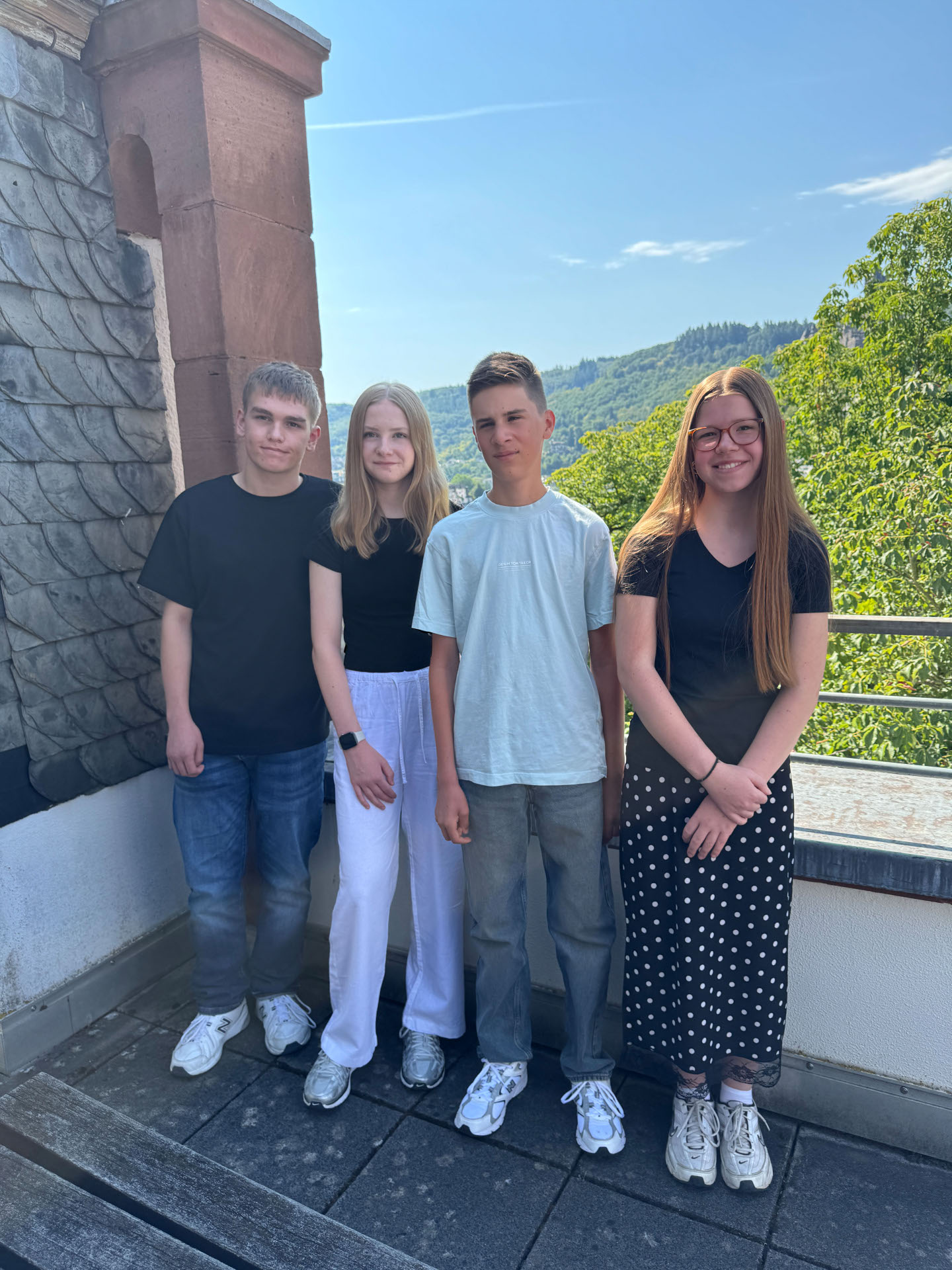 Zu sehen sind 4 junge Personen, welche nun die Ausbildung oder ein Partikum in der Kreisverwaltung absolvieren. Sie stehen auf der Dachterrasse, neben ihnen ist ein Teil des Daches zu sehen, hinter ihnen sieht man frühne Bäume. v. l.: Philipp Mohrs, Maren Emmerich, Finn Clausen, Jolaine Piellusch