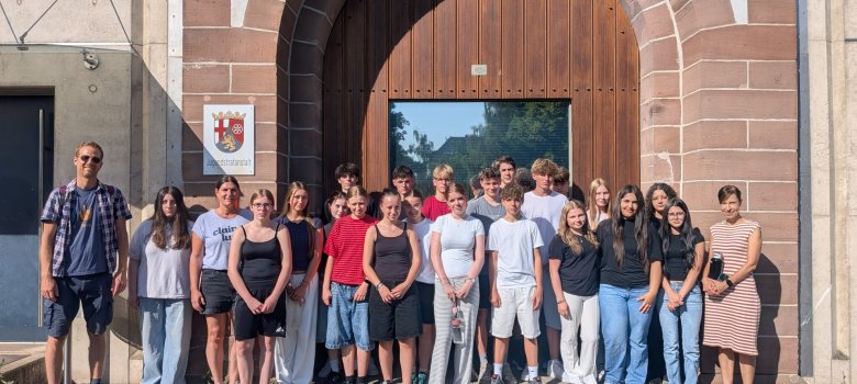 „Mit der Klasse in den Knast“ – 9b der Realschule plus Cochem zu Besuch in Wittlich Zu sehen ist eine Klasse, vor der Jugendstrafanstalt Wittlich. Die Schülerinnen und Schüler stehen in Reihen vor der Eingangstür. Links neben der Klasse befindet sich ein Lehrer und rechts daneben eine Lehrerin.