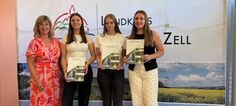Neuer Lebensabschnitt: Wir begrüßen unsere neuen Nachwuchskräfte im 2. und 3. Einstieg-samt! Zu sehen sind vier weibliche Personen der Kreisverwaltung Cochem-Zell. Diese stehen in einer Reihe. Links steht die Landrätin Frau Anke Beilstein. Daneben befinden sich zwei neue Anwärterinnen des 2. Einstiegsamtes. Diese halten jeweils eine Mappe der Kreisverwaltung in der Hand mit ihrer Patenschaftszuweisung. Zwischen der Landrätin und den Anwärterinnen steht die Patin der neuen Nachwuchskräfte.
