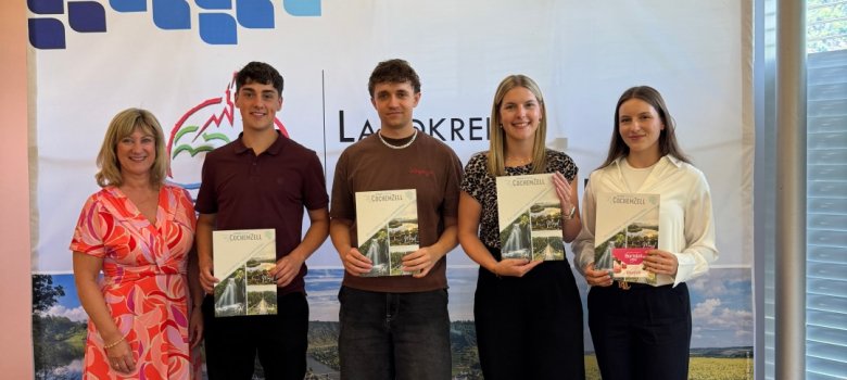 Neuer Lebensabschnitt: Wir begrüßen unsere neuen Nachwuchskräfte im 2. und 3. Einstieg-samt! Zu sehen sind 5 Personen, welche in einer Reihe stehen. Links befindet sich Landrätin Frau Anke Beilstein. Daneben befinden sich drei neue Anwärterinnen und Anwärter des 3. EInstiegsamt. Diese halten jeweils die Mappe der Kreisverwaltung in der Hand mit der Zuweisung ihrer Patenschaft. Rechts steht die Patin der drei neuen Nachwuchskräfte.