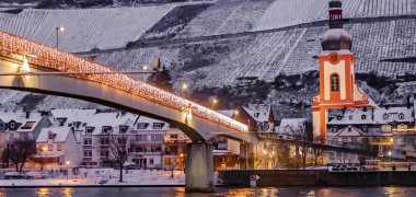 Tourismuscluster Eifel | Mosel | Hunsrück ruft zur Mitgestaltung auf Zu sehen ist die Cochemer Brücke bei Abenddämmerung im Winter. Alles ist mit Lichtern ausgeschmückt.