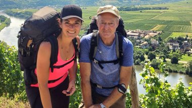 Auf dem Bild zusehen sind Gerhard und Rebecca Schindler, die gerade am wandern sind mit Blick auf die Mosel.