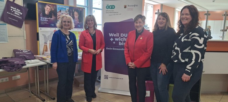 Tag des Gesundheitsamtes in der Kreisverwal-tung Cochem-Zell am Donnerstag, 19.03.2026 Das Foto zeigt von links nach rechts: Leitende Kreisverwaltungsdirektorin Barbara Schatz-Fischer, Landrätin Anke Beilstein, Ärztliche Leitung Gesundheitsamt Dr. Heidi Treiber, Mitarbeiterinnen Gesundheitsamt Maren Höhnen-Heins und Marion Ramler. Sie stehen im Bürgerbüro der Kreisverwaltung Cochem-Zell vor Stellwänden, die mit Informationsplakaten bestückt sind. Auf einem Tisch im Hintergrund lieht zudem weiteres Informations- und Werbematerial.