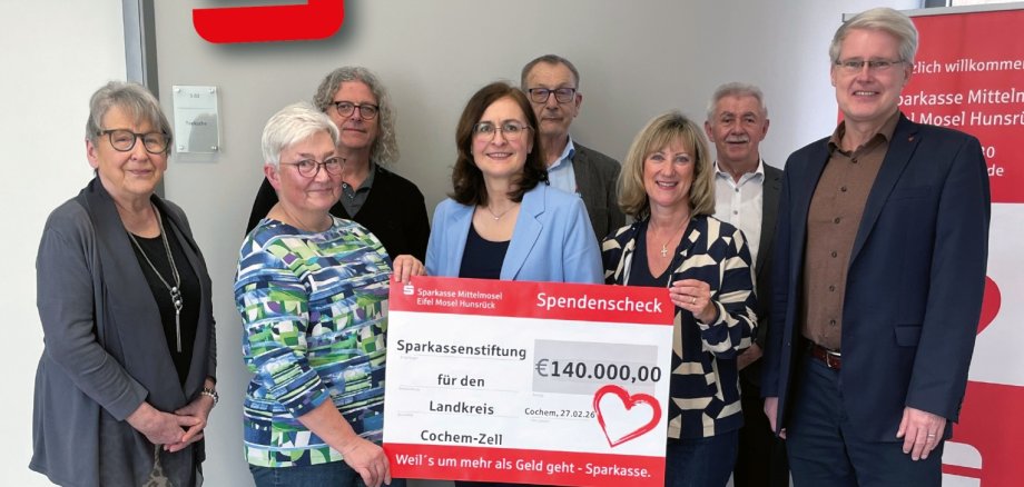 Sparkassenstiftung fördert
Bildung, Soziales und Kultur mit 140.000 Euro Das Foto zeigt v.l.: Inge Krämer, Hildegard Moritz, Thomas Krämer, Bettina Pellio, Geschäftsführerin, Helmut Braunschädel, Landrätin Anke Beilstein, Andreas Peifer und Eric Westerheide, Vorsitzender des Vorstandes Sparkasse. Die Personen in der Mitte halten einen großen Symbolscheck in den Händen, auf dem der gespendete Betrag zu lesen ist.
