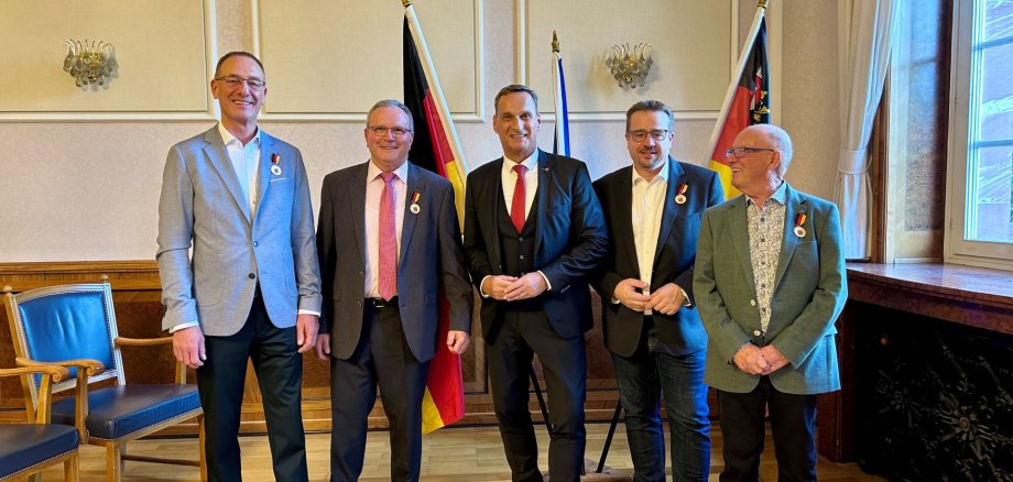 Auf dem Foto sind von links folgende Personen zu sehen: Günter Groß, Berthold Berenz, Joachim Rodenkirch, Sebastian Seifert und Karl-Heinz Hilgenberg. Sie stehen in einem Saal mit Holzboden vor einem Aufsteller mit drei Flaggen (Deutschland, unbekannt, Rheinland-Pfalz) in einer Reihe.