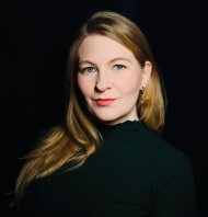 María Sól Ingólfsdóttir Das Foto zeigt die Sängerin María Sól Ingólfsdóttir. Der Bildhintergrund ist schwarz, die Sängerin trägt ein schwarzes Oberteil, sie trägt die Haare offen und blickt in die Kamera.