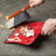Zigarettenstummel werden mit dem Kehrblech aufgekehrt.