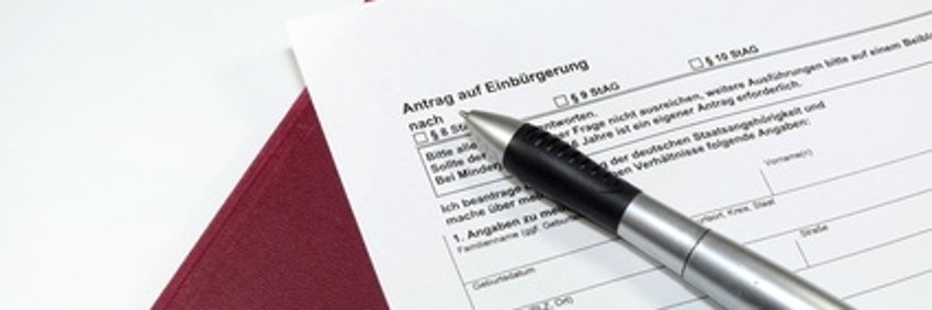 Dargestellt ist ein Einbürgerungsantrag sowie einen Reisepass.