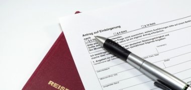 Dargestellt ist ein Einbürgerungsantrag sowie einen Reisepass.