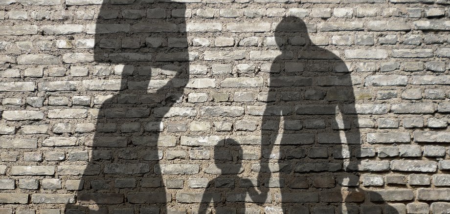 Schatten einer Flüchtlingsfamilie mit Koffern.
