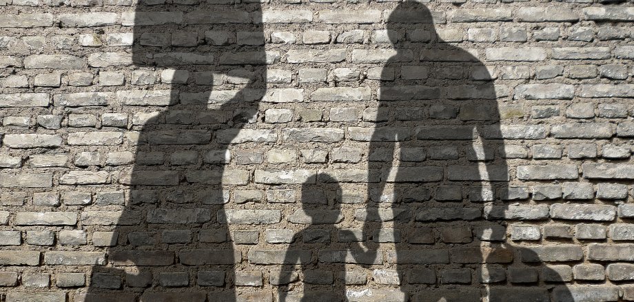 Schatten einer Flüchtlingsfamilie mit Koffern.