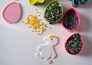 Verschiedene Schälchen mit Bügelperlen. Außerdem ist das Bügelperlenmotiv einer Ente zu erkennen.