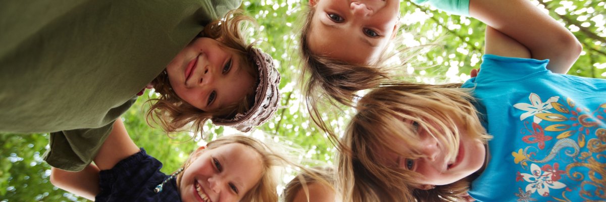 Dargestellt sind fünf Kinder die im Kreis stehen und Ihr Köpfe zusammenstecken. Dargestellt sind fünf Kinder die im Kreis stehen und Ihr Köpfe zusammenstecken.