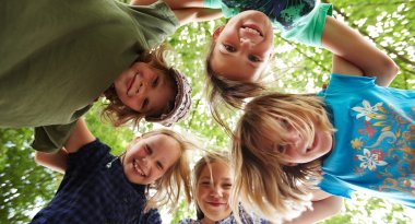 Dargestellt sind fünf Kinder die im Kreis stehen und Ihr Köpfe zusammenstecken. 