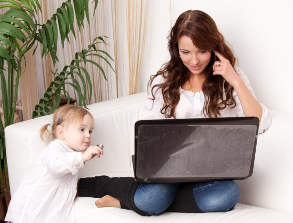 Mutter mit Kind arbeitet am Laptop