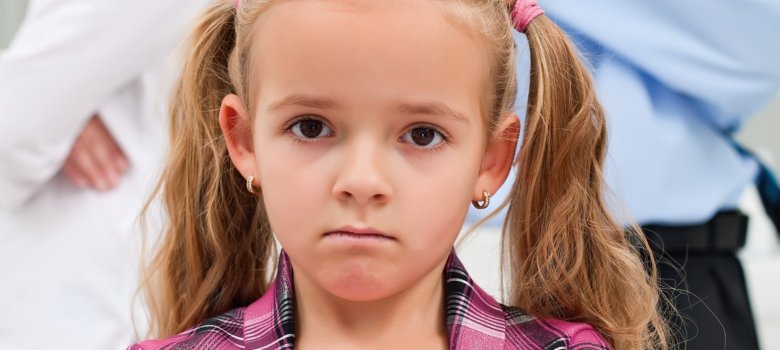 Konflikt in einer Familie, Mutter und Vater im Hintergrund, kleines Mädchen im Vordergrund mit verschränkten Armen. Konflikt in einer Familie, Mutter und Vater im Hintergrund, kleines Mädchen im Vordergrund mit verschränkten Armen.