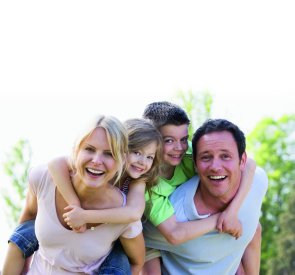 Mann und Frau tragen zwei Kinder auf dem Rücken. 