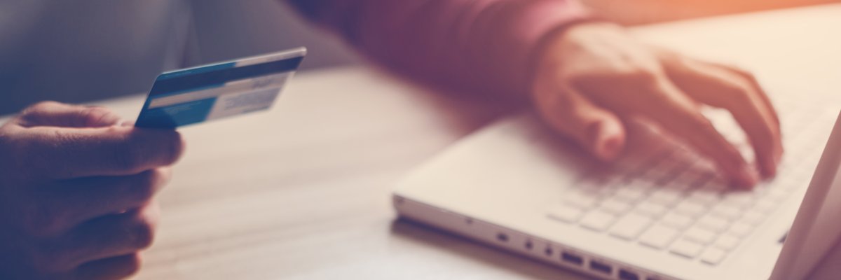 Mann hält eine Bankkarte. Laptop steht auf dem Tisch. Mann hält eine Bankkarte. Laptop steht auf dem Tisch.