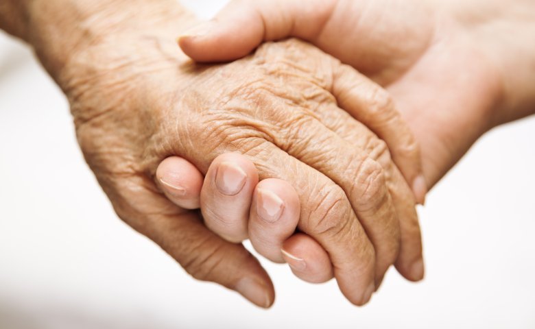 Haltende Hände eines Senioren und eines Erwachsenen