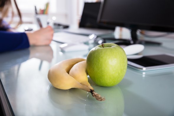 Auf einem Tisch liegt eine Banane sowie ein Apfel