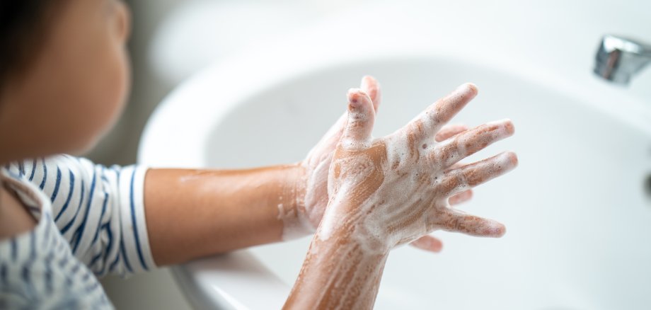 Kind wäscht sich seine Hände über dem Waschbecken mit Seife.