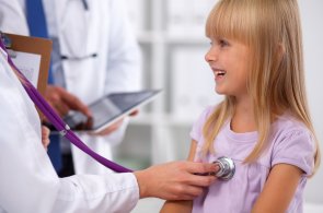 Ein Kind wird von einem Arzt mit dem Stetoskop untersucht. 