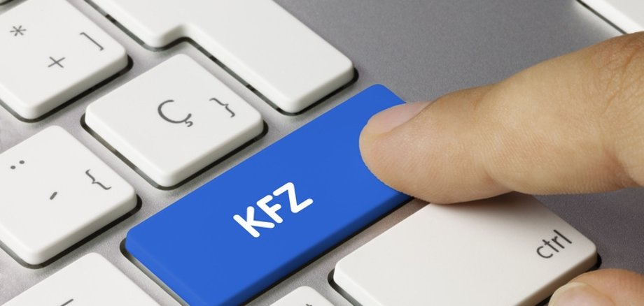 Tastatur mit dem Wort KFZ. Ein Finger tippt auf diese Taste.