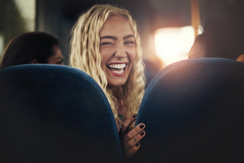 Young woman laughing and winking while sitting on a bus