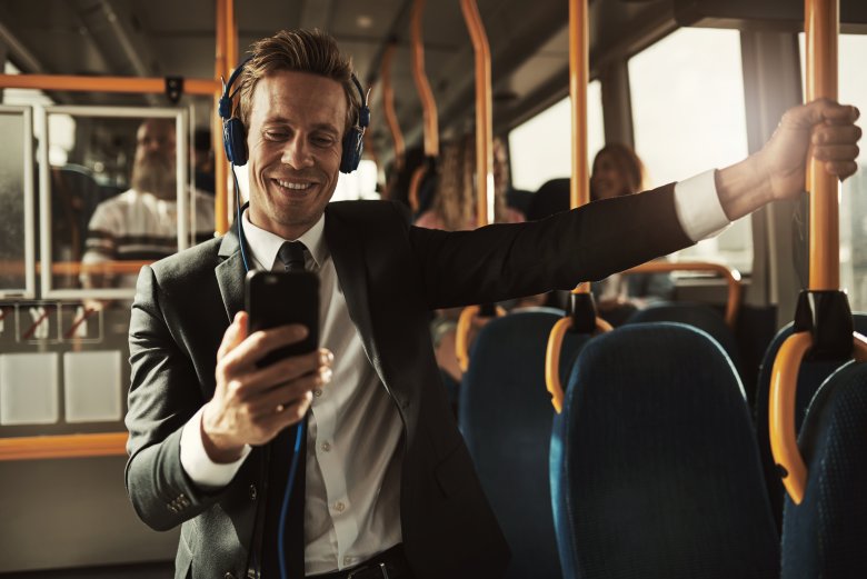Smiling businessman listening to music while riding on a bus