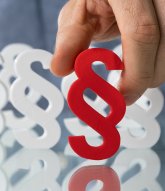 Hand hält ein Paragrafenzeichen