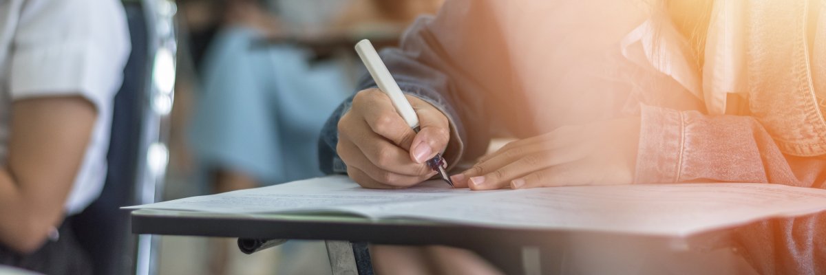 Mädchen schreibt mit einem Stift auf einen Block Mädchen schreibt mit einem Stift auf einen Block