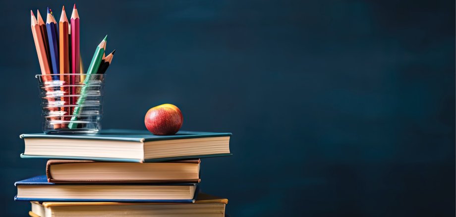 Motivbild Schulbuchausleihe, Stabel Bücher mit Stiftebecher und einem Apfel