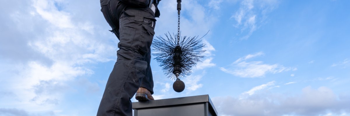 Schornsteinfeger mit Ofenrohrhut auf dem Dach.