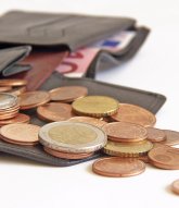 Dargestellt ist ein offenes Portmonee mit Kleingeld und eine 10 € Schein im Hintergrund.