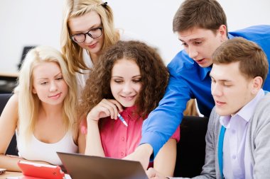 Junge Menschen sitzen zusammen an einem Laptop.