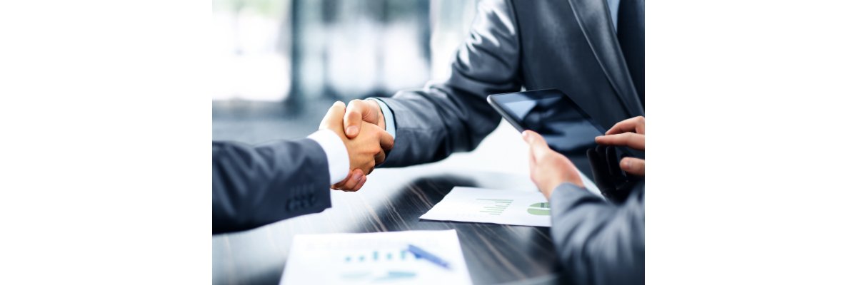 Dargestellt sind zwei Menschen im Anzug, die sich die Hände schütteln. Dargestellt sind zwei Menschen im Anzug, die sich die Hände schütteln.