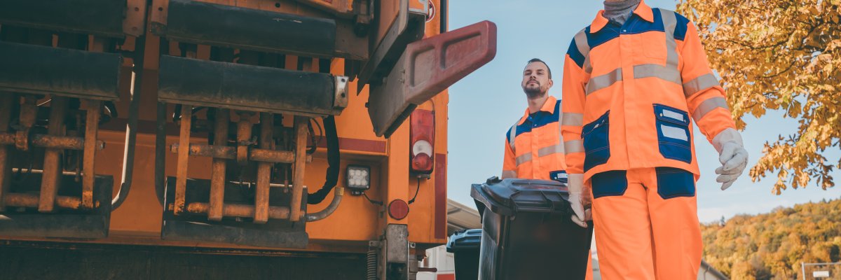 Two refuse collection workers loading garbage into waste truck Kreiswerke Cochem-Zell - Abfallwirtschaft -
