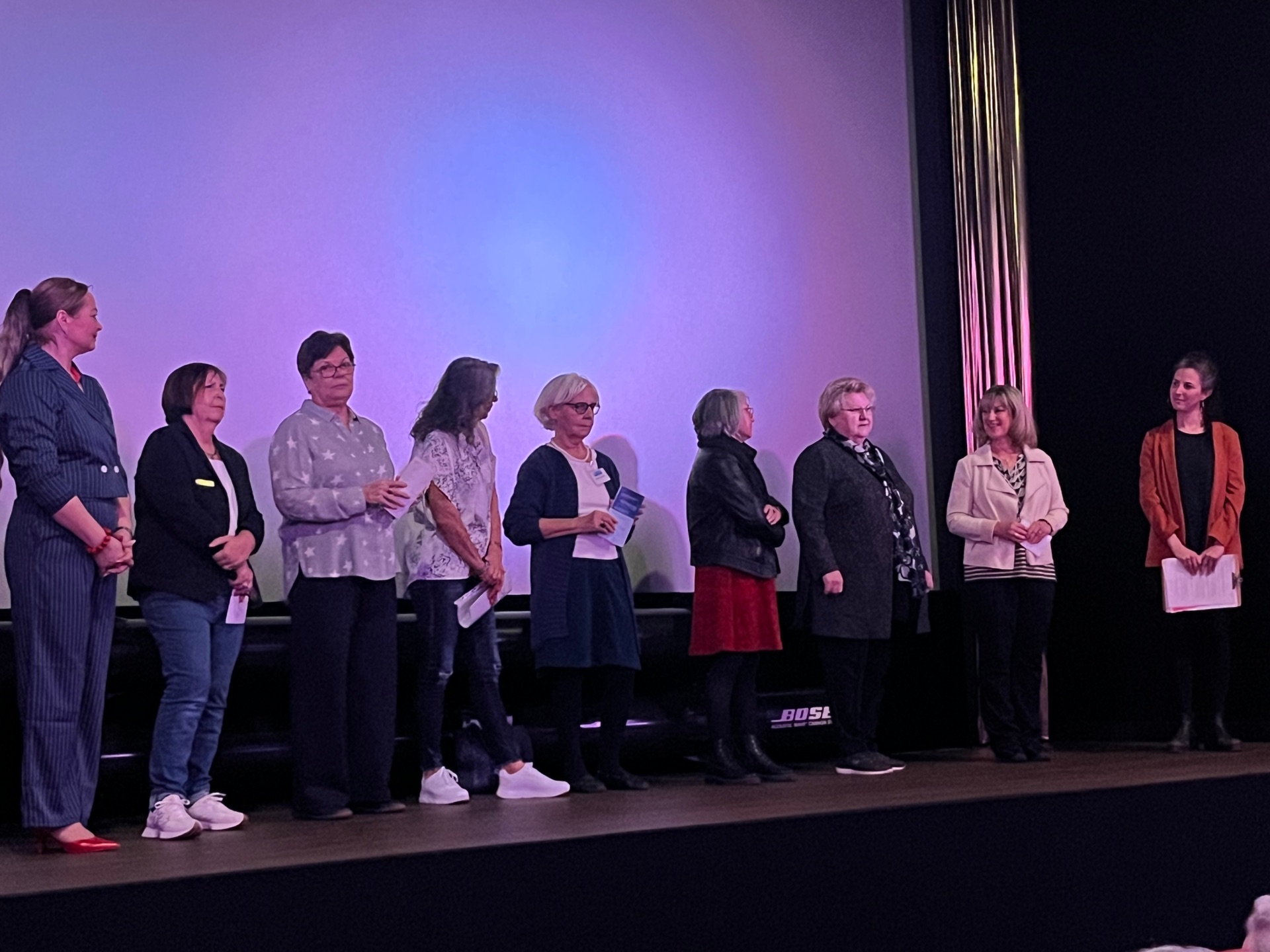 Internationaler Frauentag in Cochem: Großer Zuspruch bei Benefiz-Filmvorführung - die Veranstalterinnen stehen gemeinsam in einer Reihe vor der Kinoleinwand und begrüßen das Publikum.
